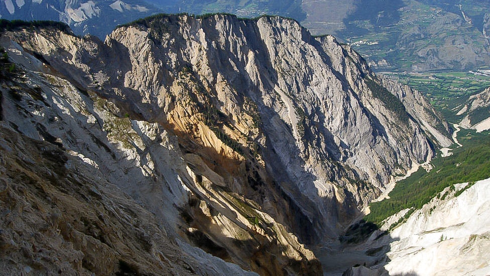 Falaises escarpées et vallée profonde sous le soleil alpin.