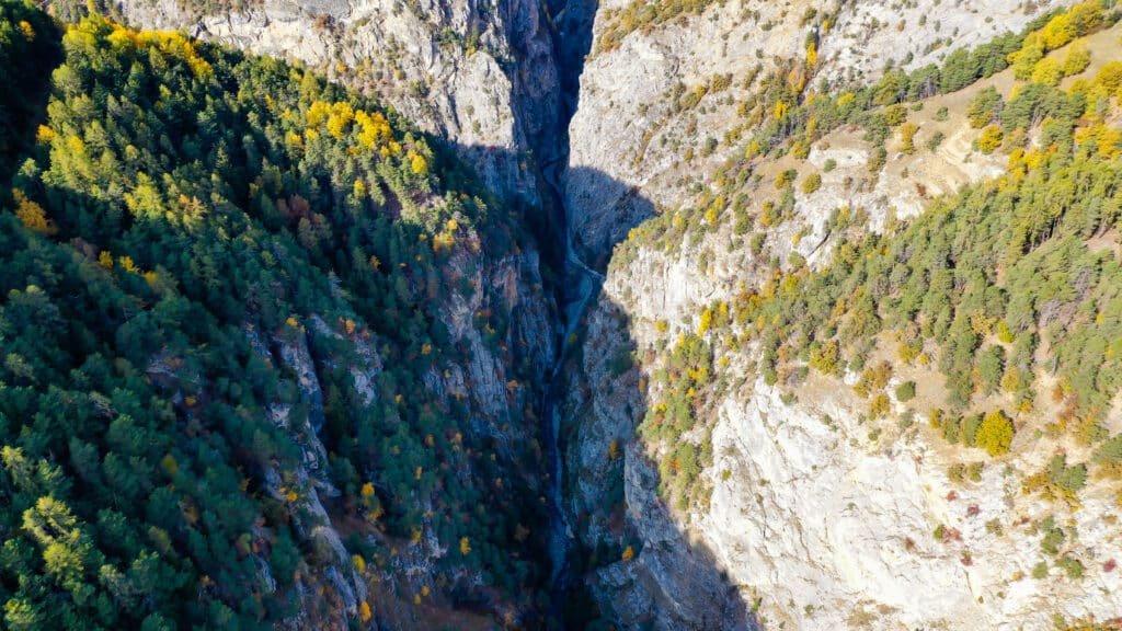Gorge de montagne boisée aux couleurs d'automne, avec rivière.