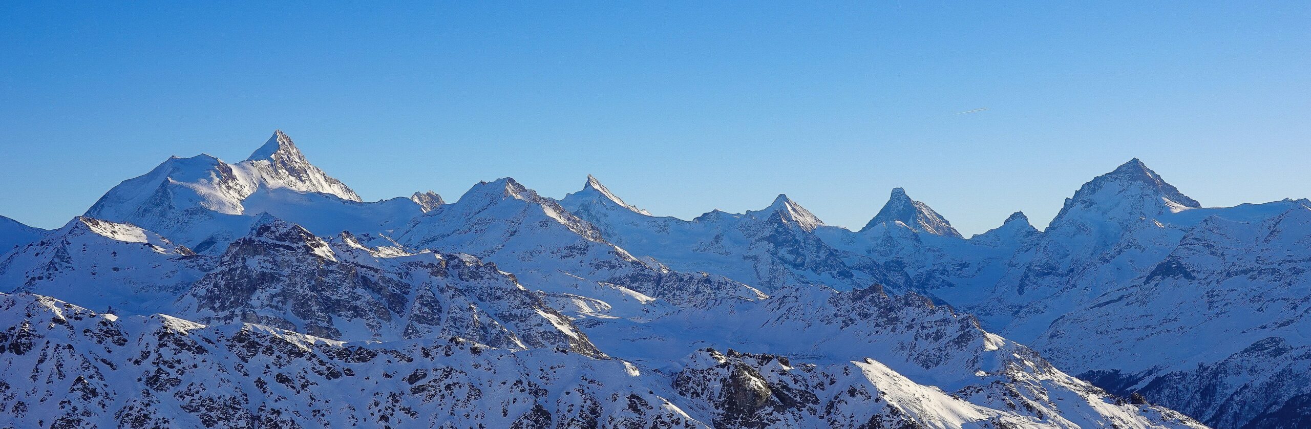Montagnes enneigées sous un ciel bleu ensoleillé.