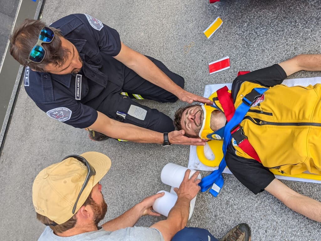 Ambulancier immobilisant un blessé sur un brancard.