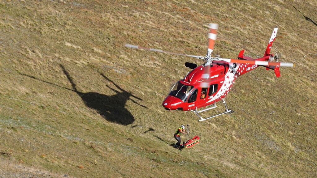 Sauvetage en montagne par hélicoptère Air Zermatt avec secouriste et brancard.