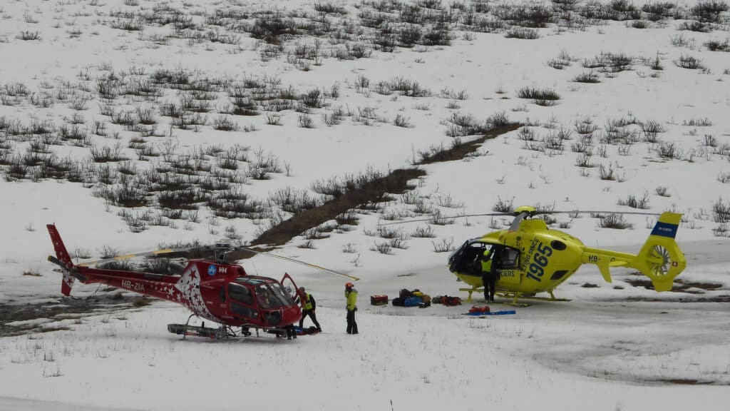 Deux hélicoptères de secours sur terrain enneigé avec personnel et équipement.