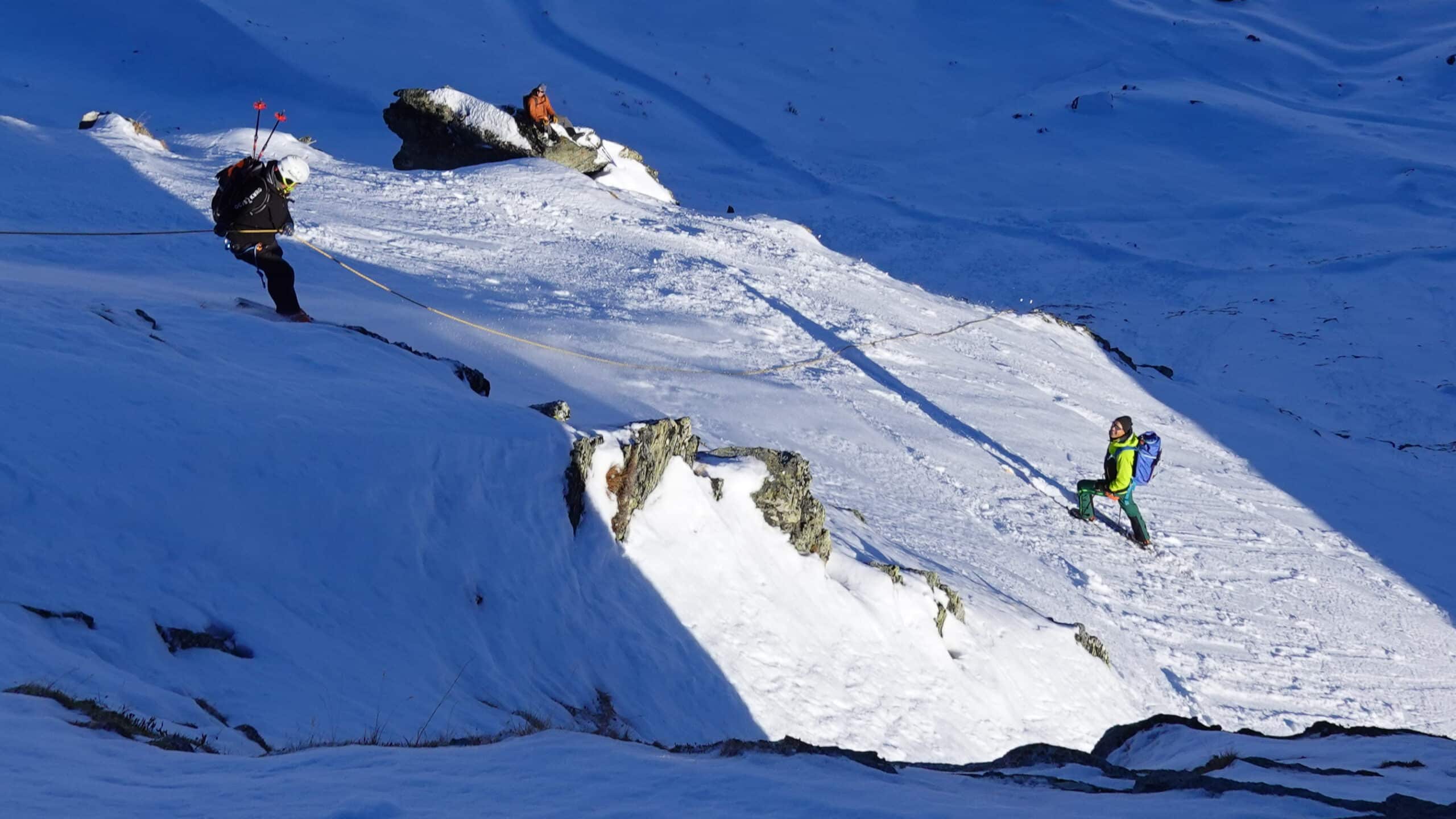 Alpinistes encordés sur pente enneigée, l'un en rappel.