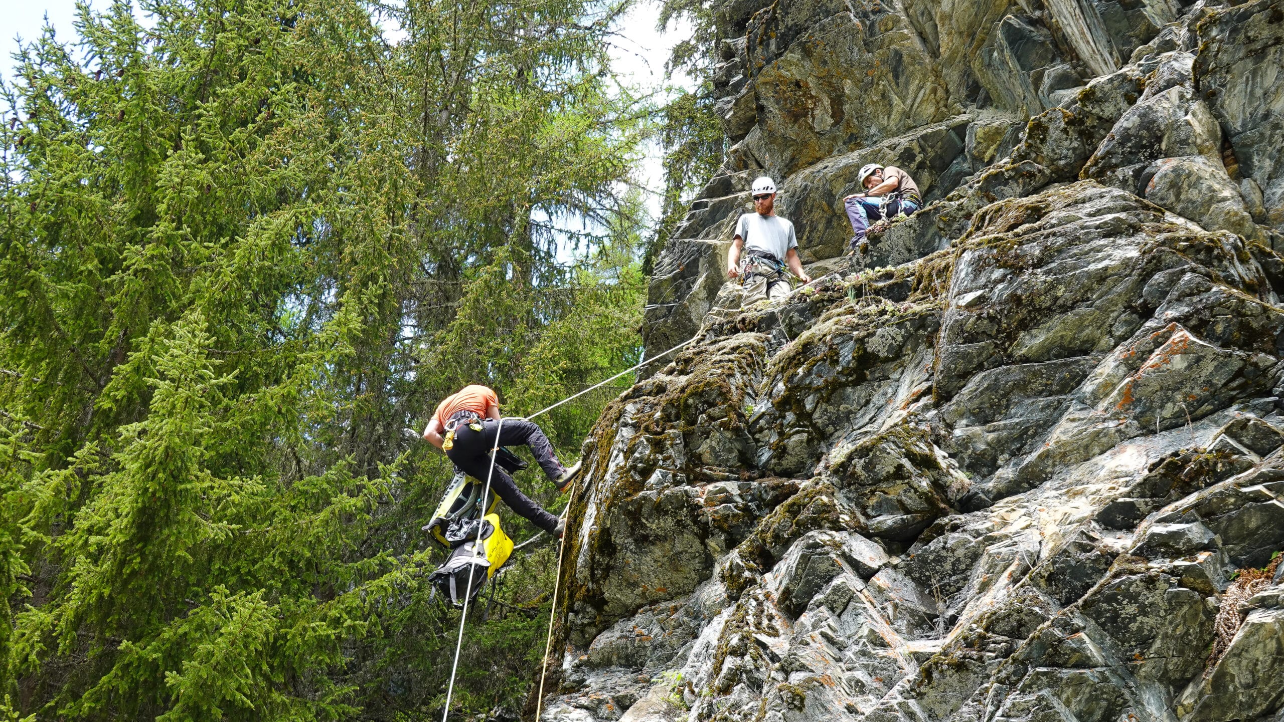 Personnes faisant de la descente en rappel sur une falaise rocheuse.