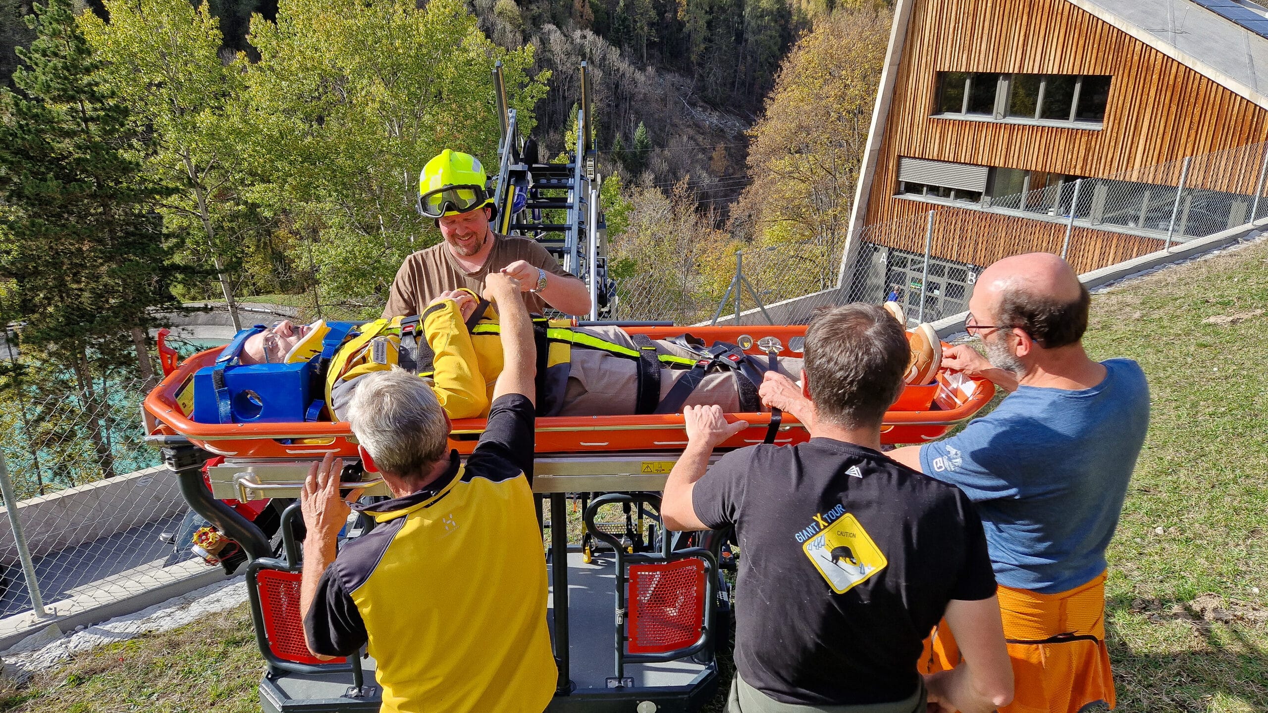 Équipe de sauvetage transportant un blessé sur brancard en montagne.