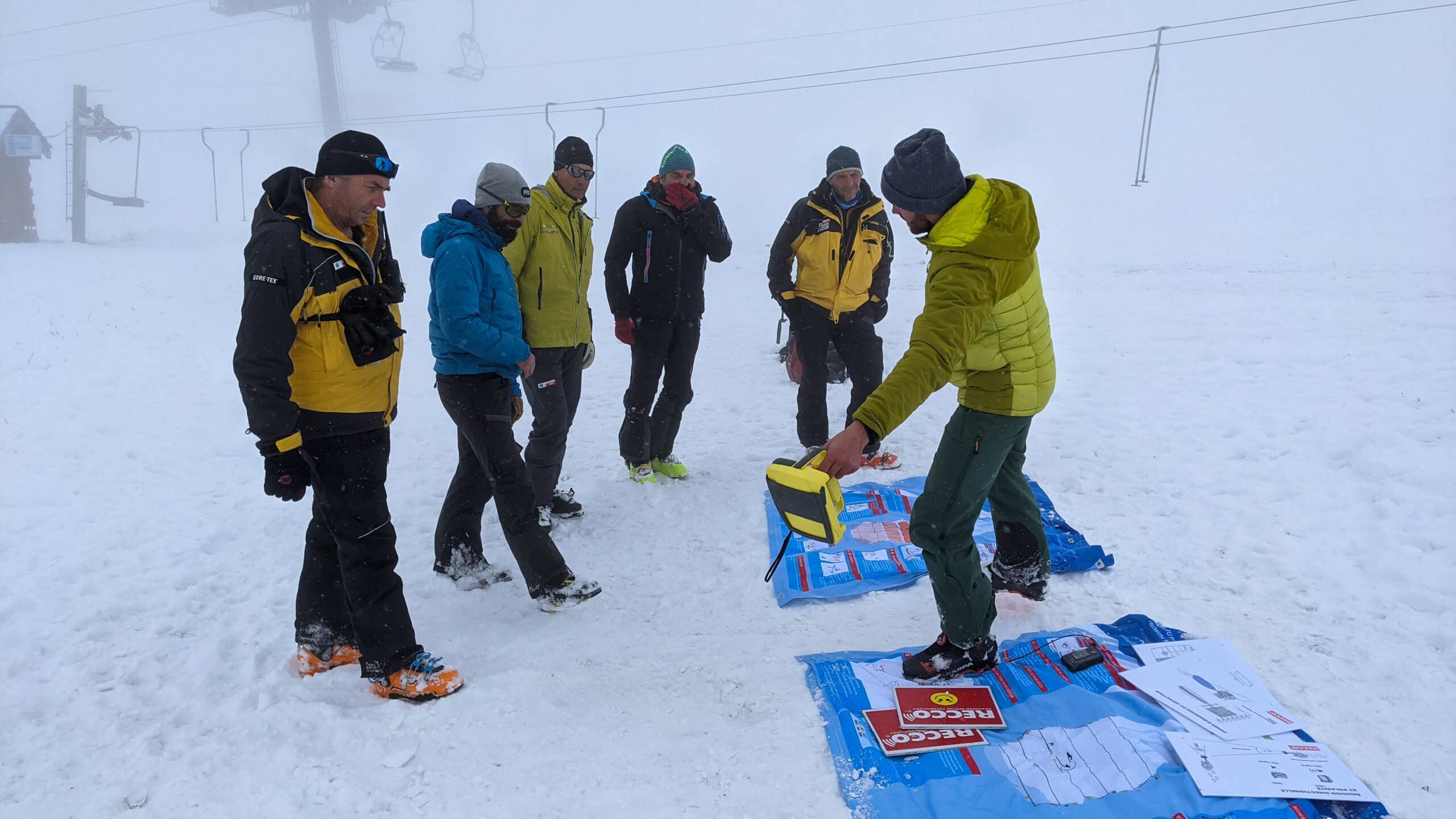 Formation RECCO en montagne : groupe sur neige brumeuse.