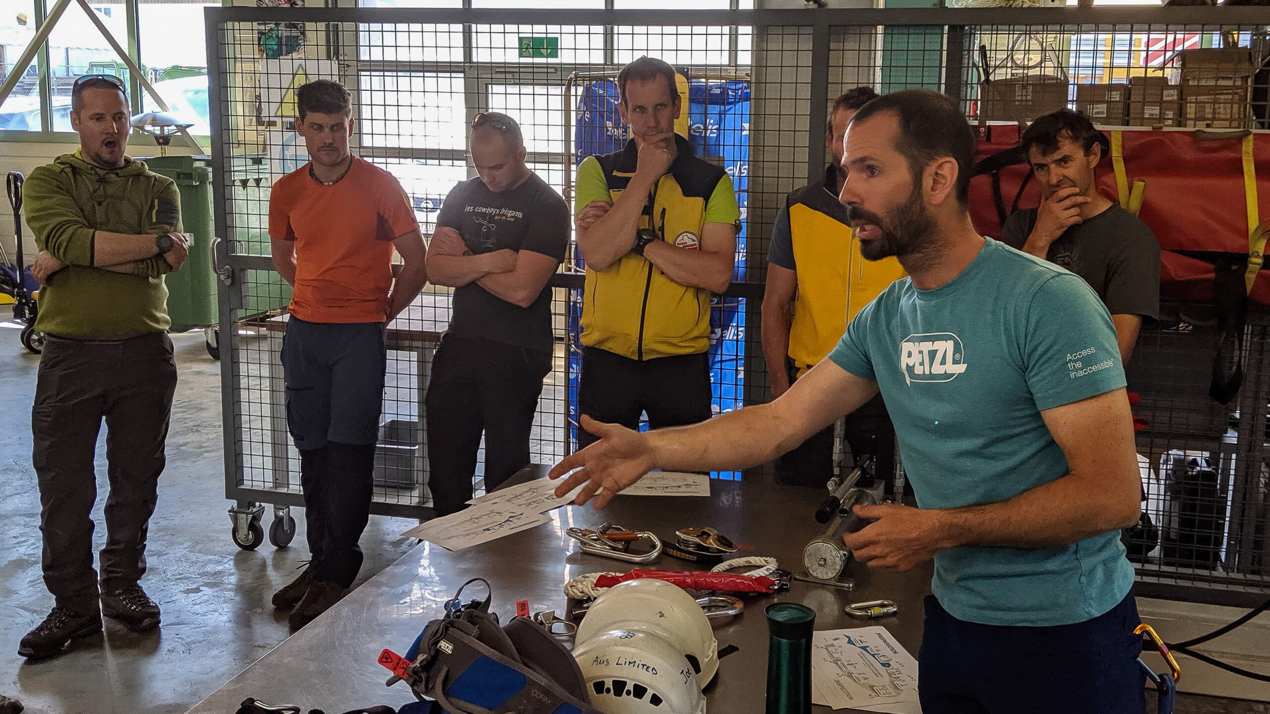 Instructeur Petzl expliquant l'équipement de sécurité à des hommes en atelier.