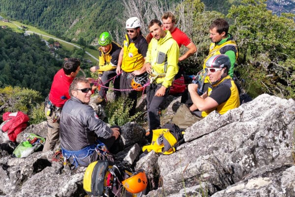 Groupe d'alpinistes équipés sur une crête rocheuse en montagne.