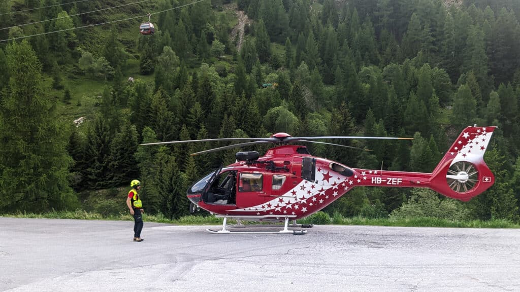 Hélicoptère de secours rouge, secouriste, forêt de montagne et télécabine.