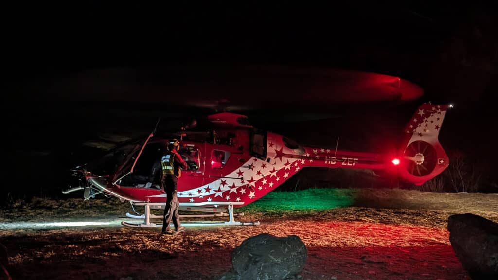 Hélicoptère de secours rouge, étoiles blanches, et personne la nuit.