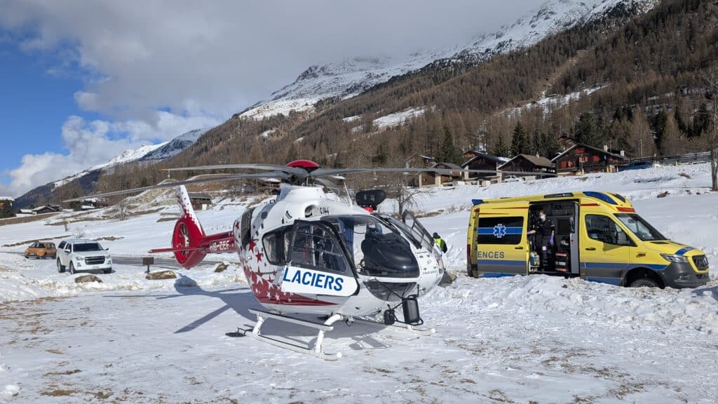 Hélicoptère et ambulance de secours en montagne enneigée.